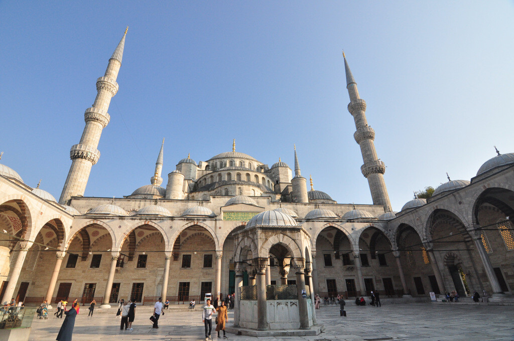 The cascading domes of the Blue Mosque viewed from the courtyard, with visitors walking around. photo by Serhat Engul